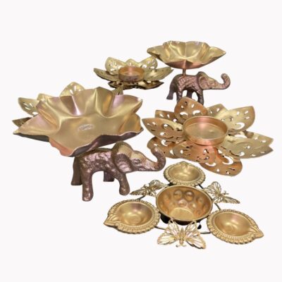 Golden Diwali tealight holder set featuring detailed elephant and butterfly motifs, lotus flower-shaped bases, and multiple diya cups, arranged on a clean white background.